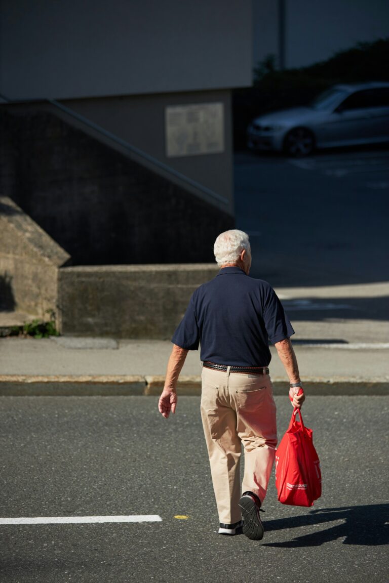 Baby Boomer aged man walking on street holding bag, posed for retirement