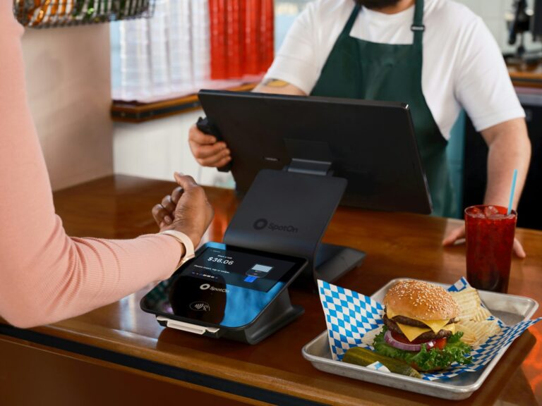 Customer paying at a restaurant counter with a burger.